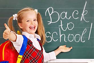 Girl pointing to words, "Back to School" on chalkboard