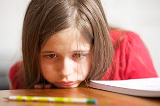 Girl looking at pencil on desk