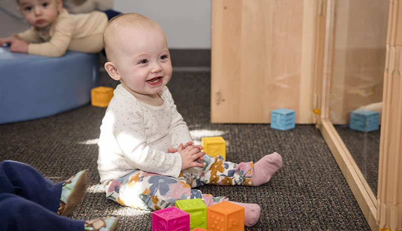 Female infant playing with blocks and laughing